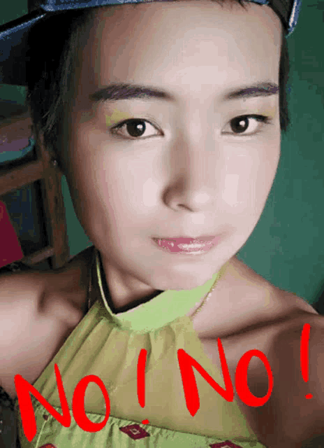 a woman wearing a hat and a green top has the word no on her shoulder
