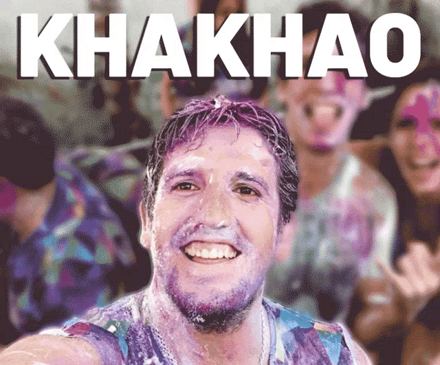 a man with purple paint on his face is smiling in front of a sign that says khakkao
