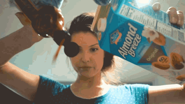 a woman is holding a box of almond breeze original