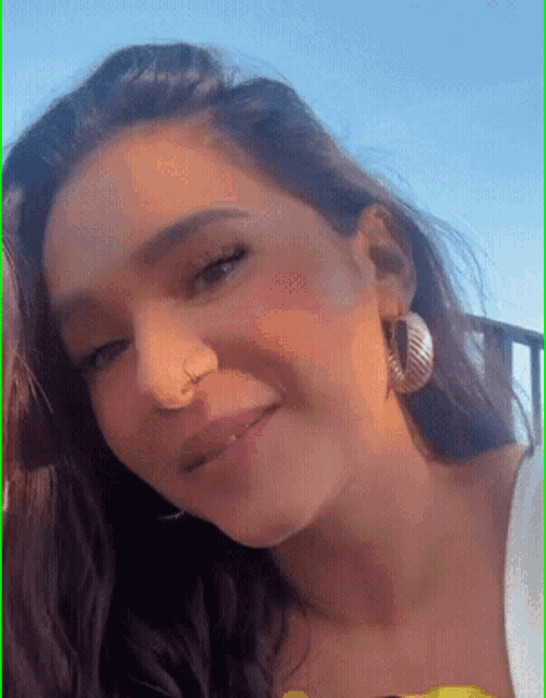 a woman with a nose ring and hoop earrings is smiling .