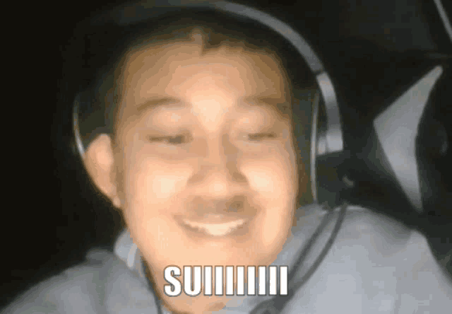 a man wearing headphones and a microphone is smiling and says suiiiiii
