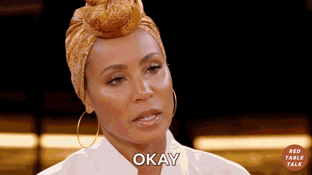 a woman wearing a head scarf and earrings says okay