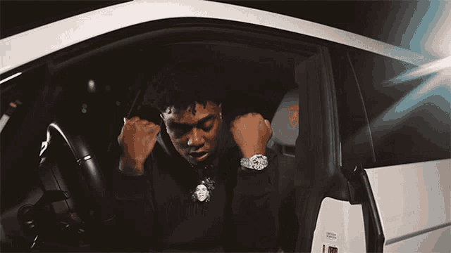 a man wearing a watch is sitting in a car with the door open