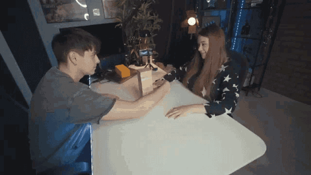 a man and a woman are sitting at a table playing a game of jenga