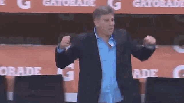 a man in a suit stands in front of a gatorade banner