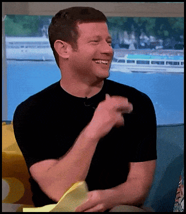 a man in a black shirt is laughing and holding a piece of paper