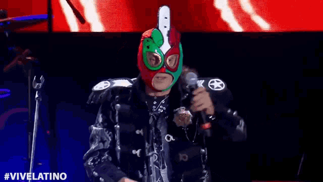 a man in a mask is standing on a stage with a microphone .