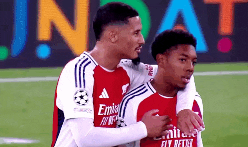two soccer players wearing emirates fly better jerseys hugging