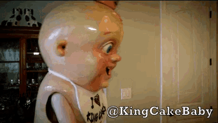 a king cake baby mascot standing in a room
