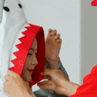a woman wearing a shark costume is being helped by a man