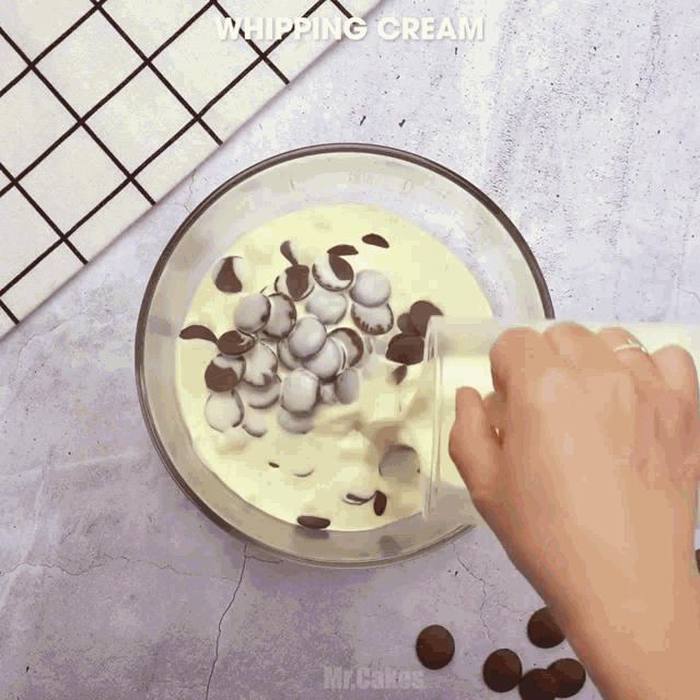someone is pouring whipping cream into a bowl with chocolate chips