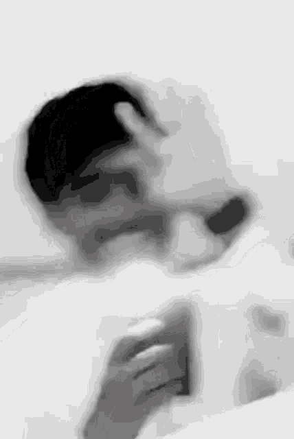 a blurry black and white photo of a man taking a selfie .