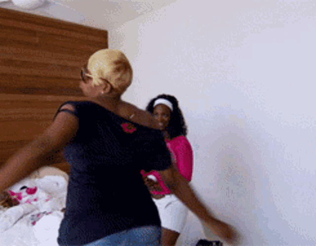 two women are dancing in a room with a white wall