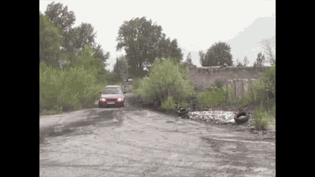 a red car is driving on a dirt road