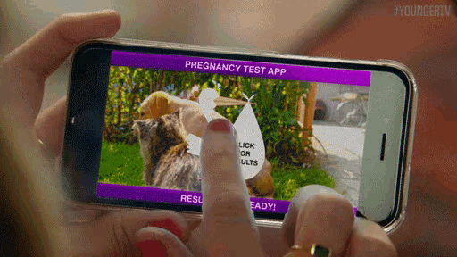 a woman holding a cell phone with a pregnancy test app on it