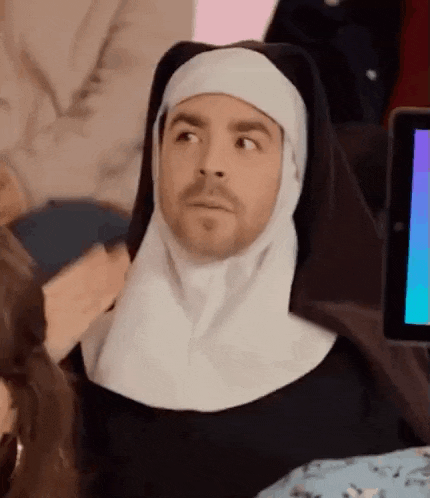 a man dressed as a nun is sitting in front of a computer screen .