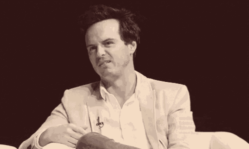 a man wearing a white shirt and a tan jacket is sitting on a white chair