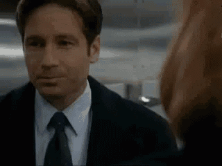 a man in a suit and tie is looking at a woman in a mirror .