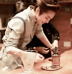 a woman is grinding coffee beans in a grinder