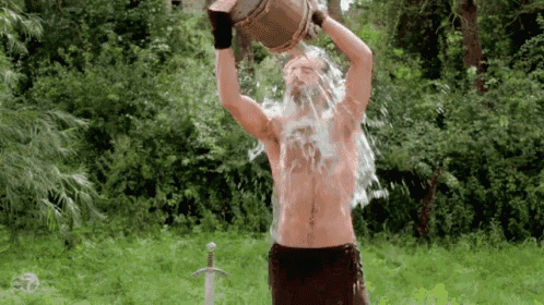 a man is pouring water from a bucket over his head .