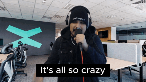 a man singing into a microphone with the words " it 's all so crazy " below him