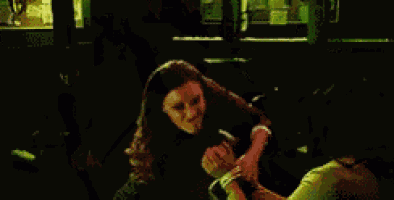 a woman in a red dress is standing in a dark room with a sword in her hand .