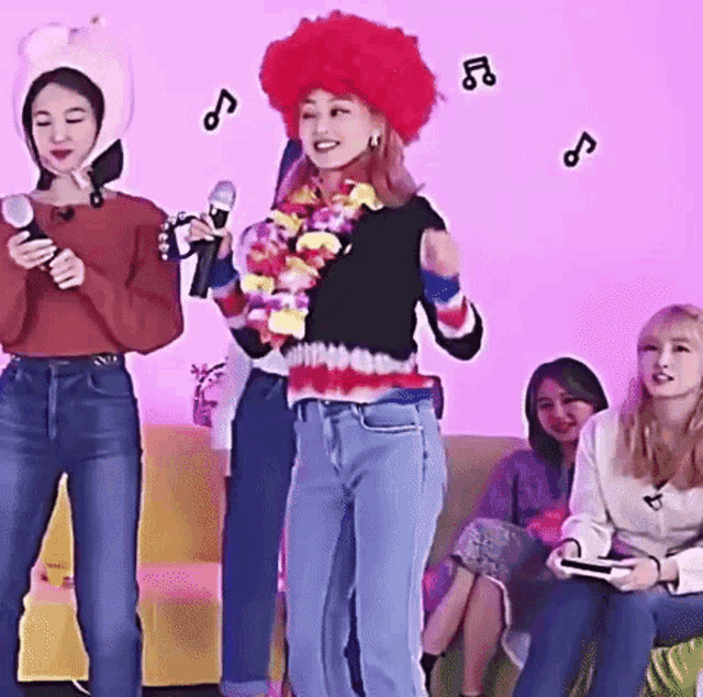 a woman wearing a red clown wig is standing in front of a group of women .