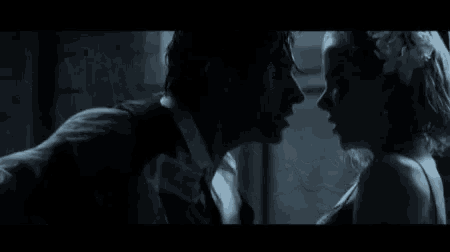 a man and a woman are laying under a canopy in bed