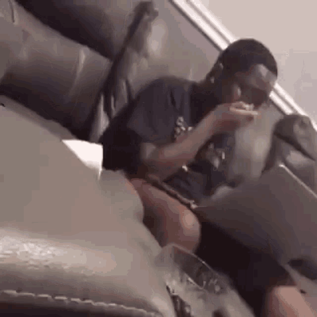 a man is sitting on a couch eating a piece of food .