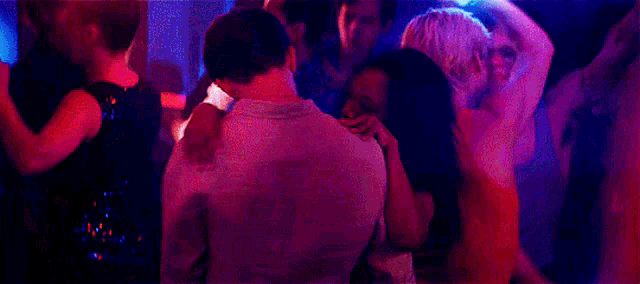 a group of people are dancing in a circle in a dark room .