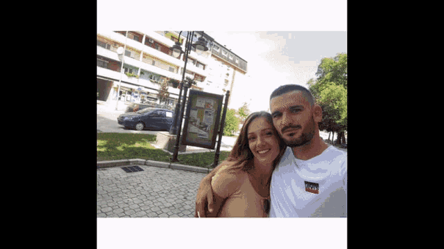 a man and a woman are posing for a picture in front of a building