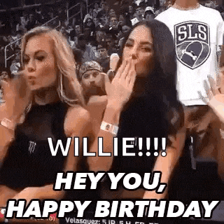 two women are sitting in the stands at a basketball game and one of them is blowing a kiss to the other .