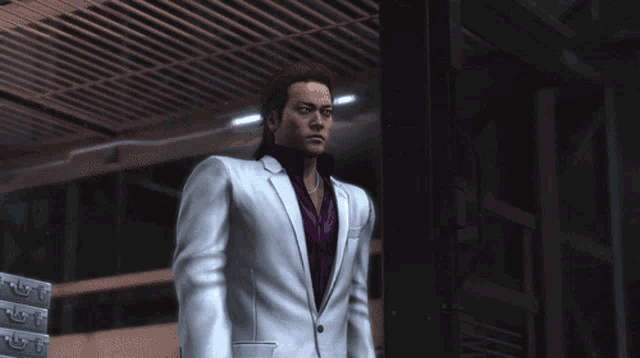 a man in a white suit with a purple tie stands in a dark room