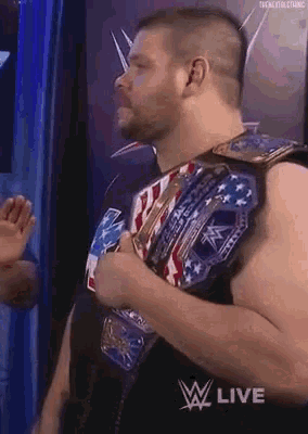 a man wearing a wrestling belt is standing in front of a blue wall .