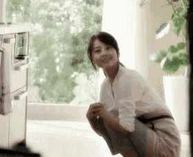 a woman is squatting on the floor in front of a window in a living room .