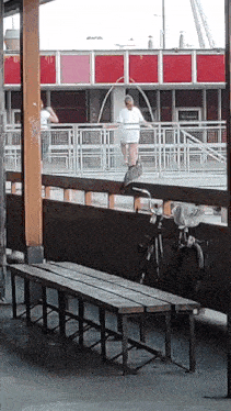 a woman in a white dress is walking on a bridge with a bicycle in front of her