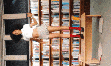 a woman standing in front of a bookshelf wearing red socks and heels