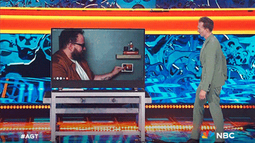 a man in a green suit is standing in front of a tv screen that says nbc