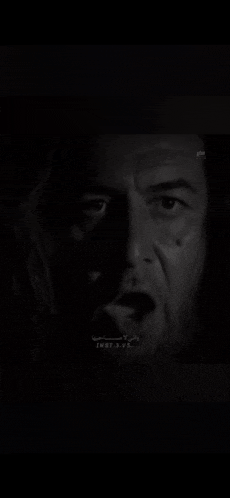 a close up of a man 's face in the dark with a surprised look on his face .