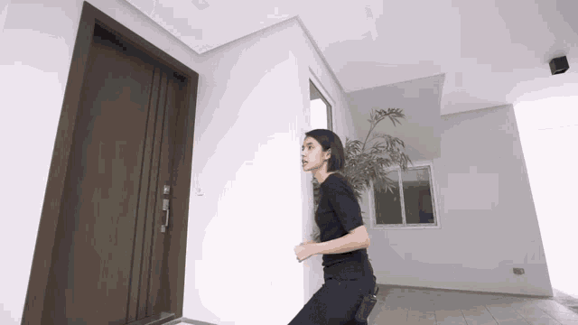 a woman in a black shirt is standing in front of a wooden door