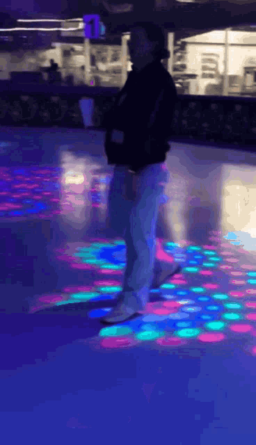 a person is standing on a ice rink with a disco light behind them