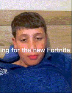 a young boy in a blue shirt is laying on a couch and looking at the camera .