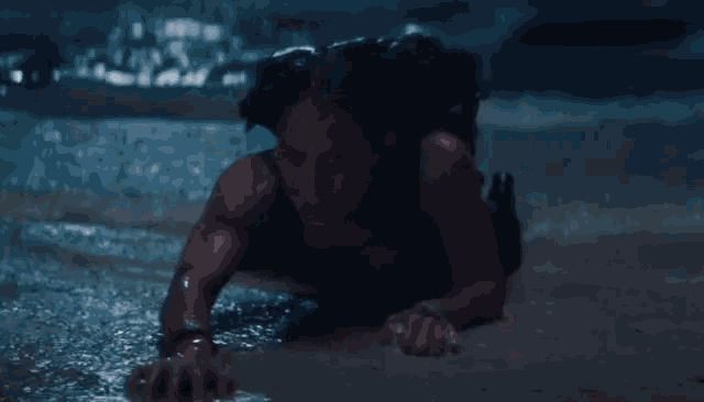 a woman is crawling through the water on the beach .