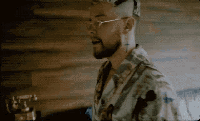 a man with glasses and a cross earring is singing