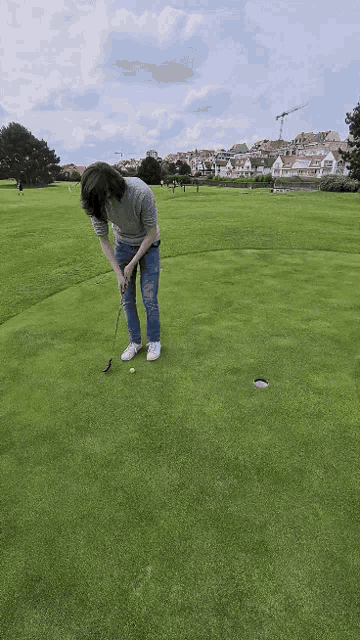 a man is putting a golf ball on a golf course