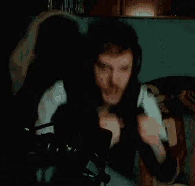 a man is sitting on a couch eating a piece of food while wearing headphones .