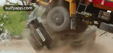 a car is stuck in the back of a truck that is going down the road .