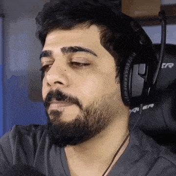 a man with a beard wearing headphones is sitting in a chair .