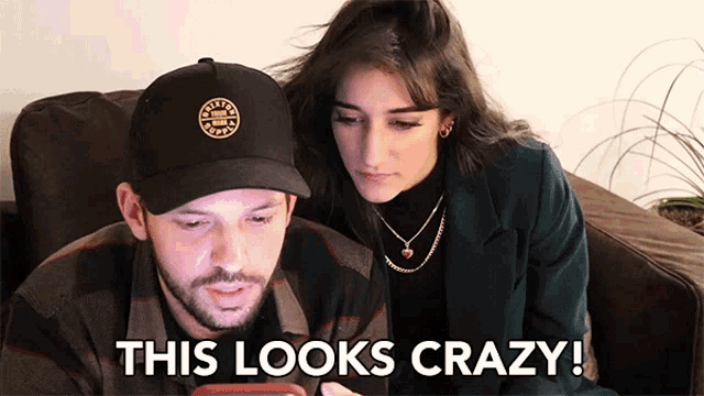 a man and a woman are looking at a phone and the man says this looks crazy