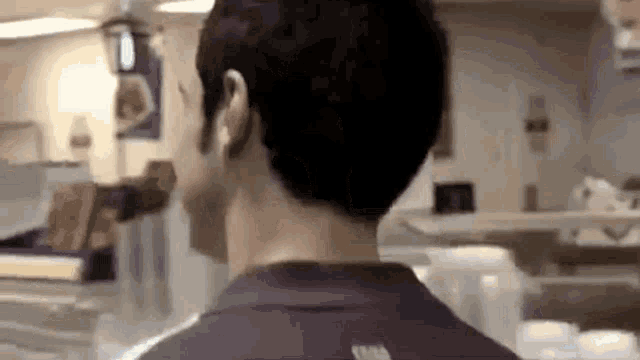 a man in a purple shirt is standing in a restaurant looking at something .